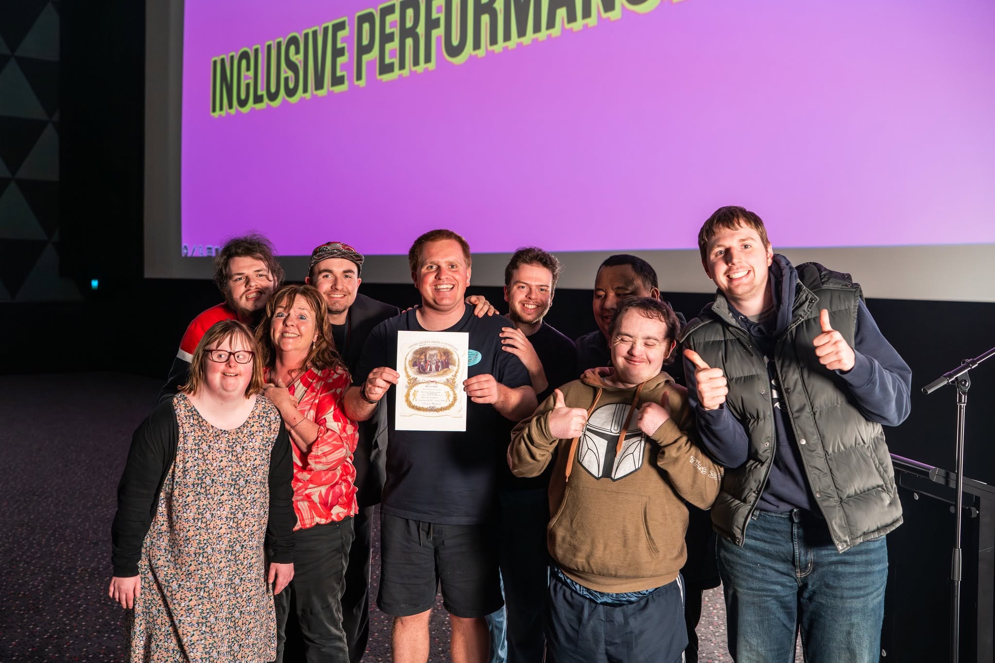 Inclusive Performance Academy ensemble celebrating together with a film award certificate